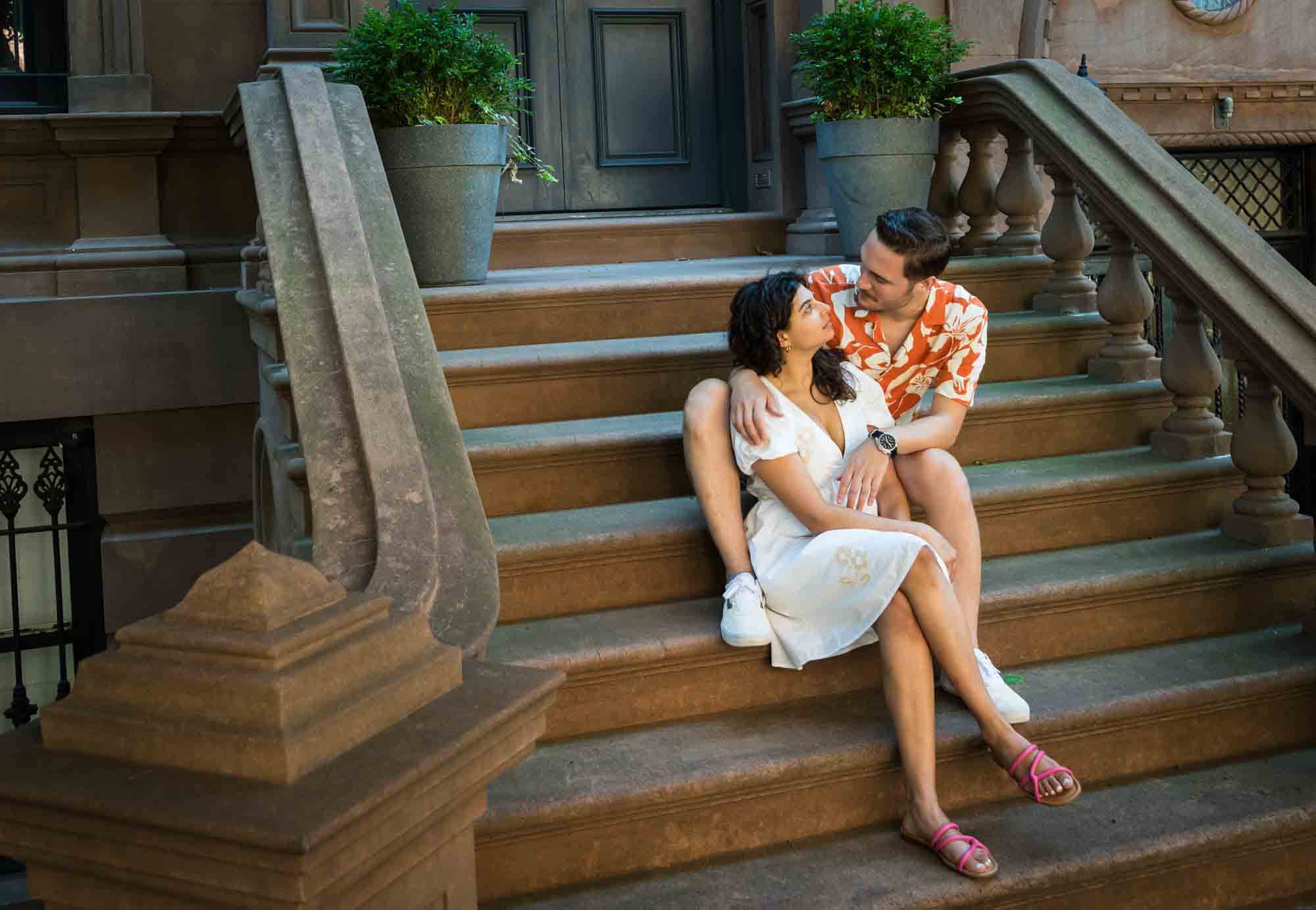 Couple looking at each other on brownstone staircase during a Brooklyn Heights surprise proposal
