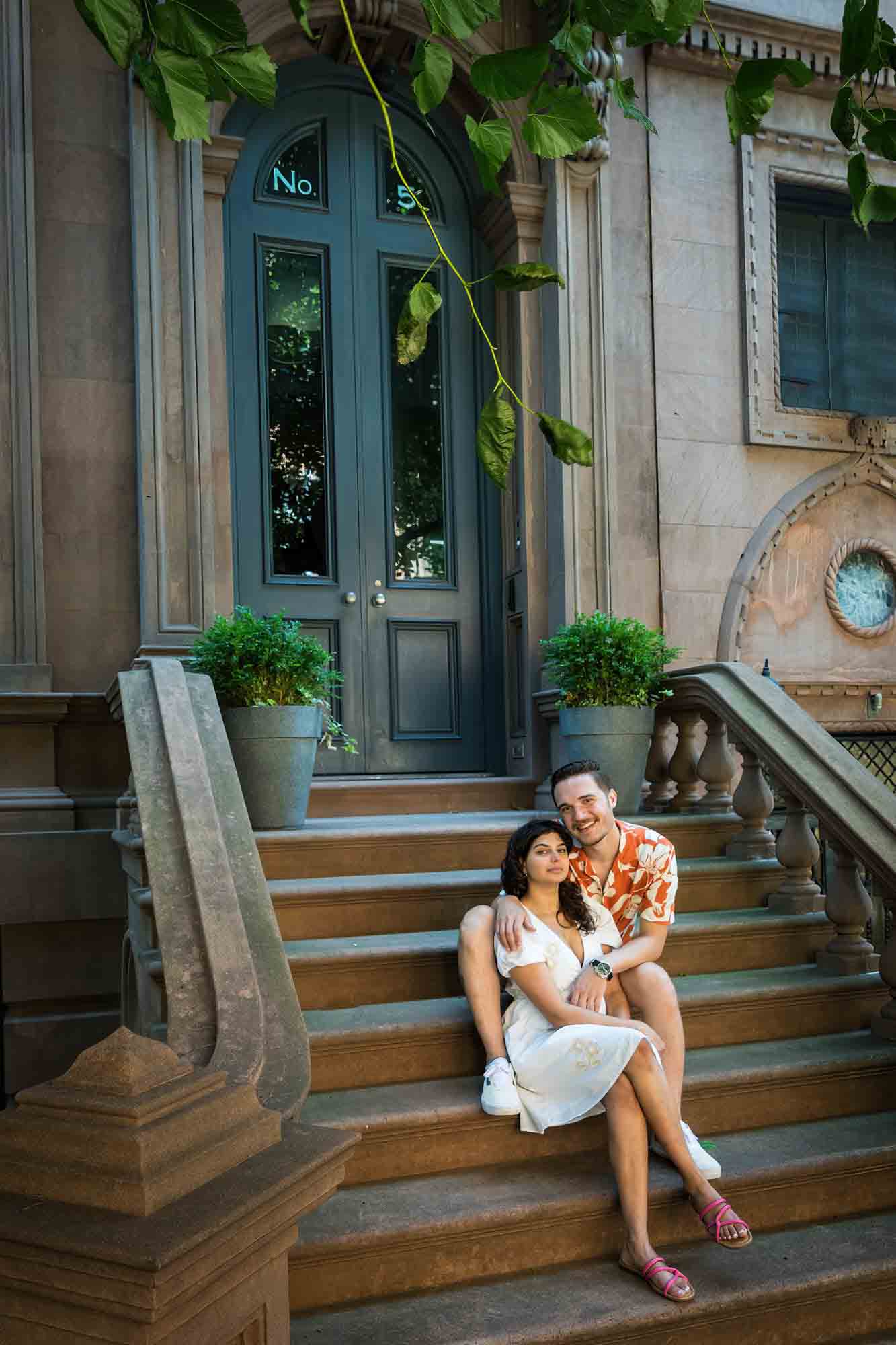 Couple sitting together on brownstone staircase during a Brooklyn Heights surprise proposal