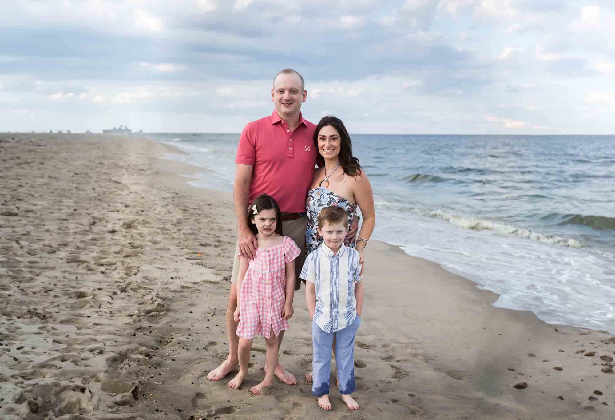 Parents and two kids standing on the beach for an article on how to get the best beach photos
