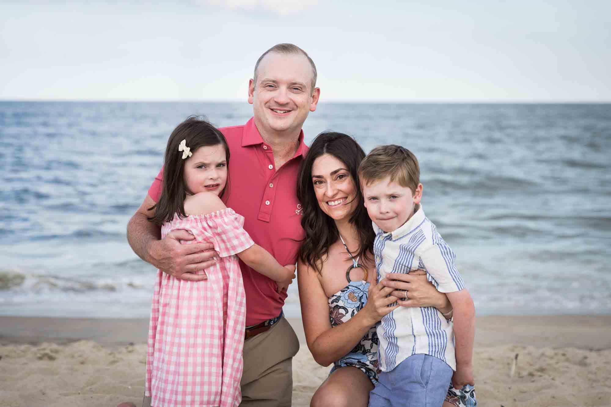 Parents and two kids sitting on the beach for an article on how to get the best beach photos