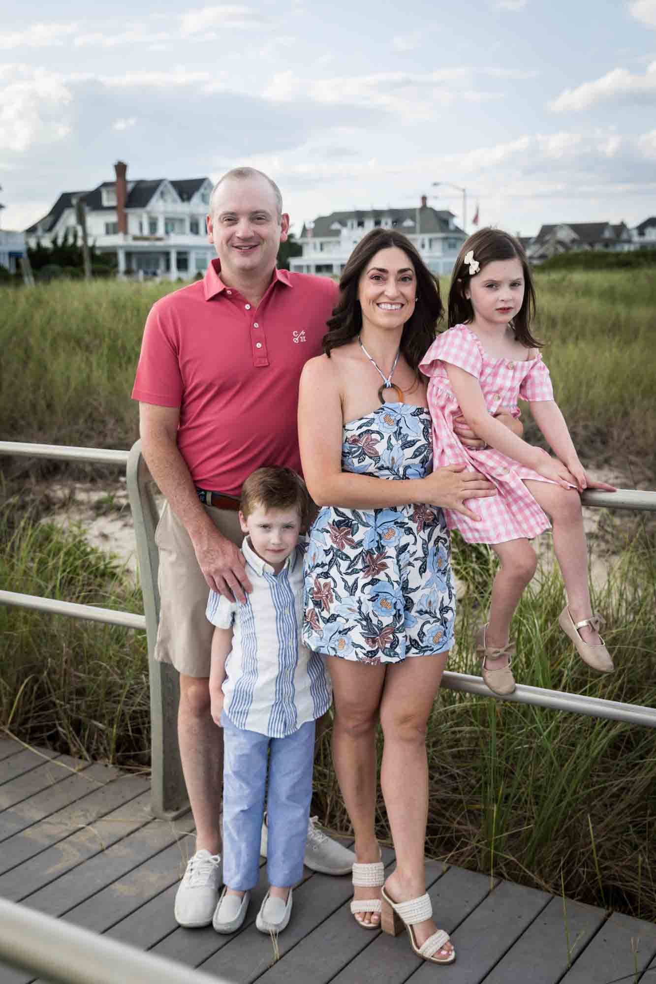 Parents and two children standing by railing in front of grass for an article on how to get the best beach photos