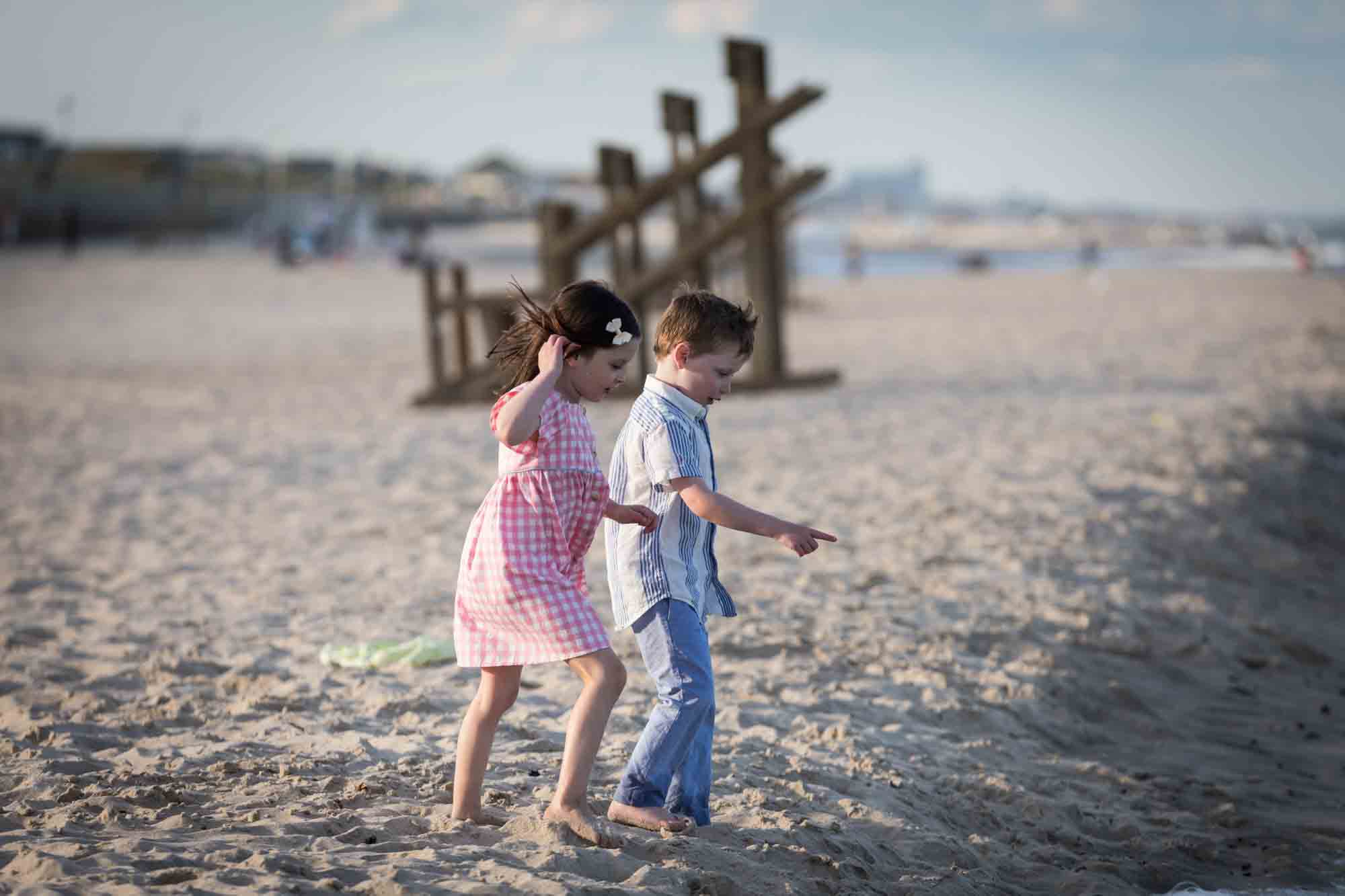 Two kids playing on the beach in front of ocean for an article on how to get the best beach photos