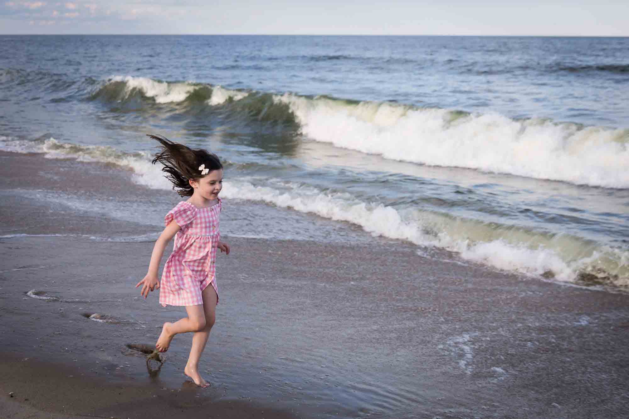 Little girl playing on the beach in front of ocean for an article on how to get the best beach photos