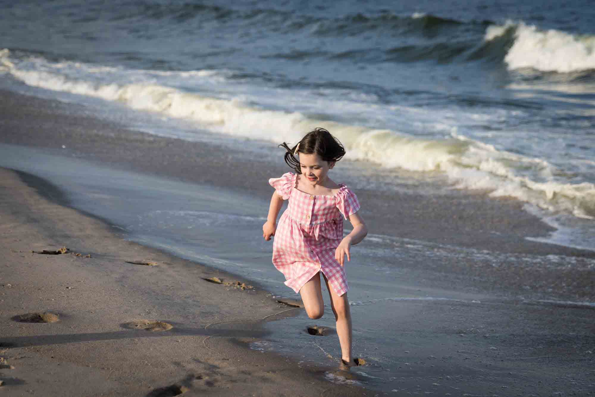 Little girl playing on the beach in front of ocean for an article on how to get the best beach photos