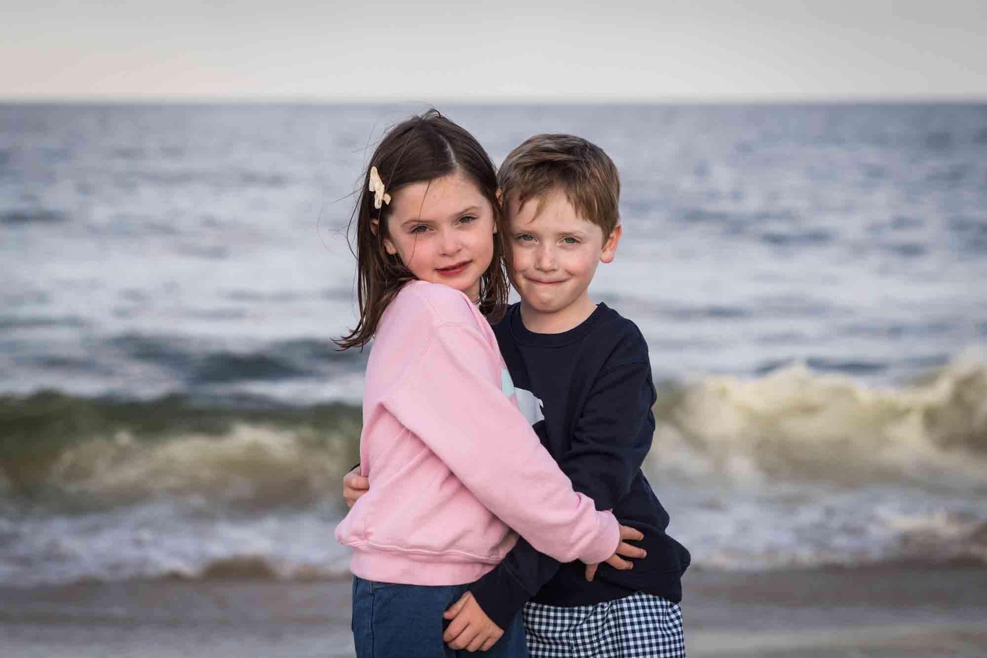 Little boy and girl hugging on beach in front of ocean