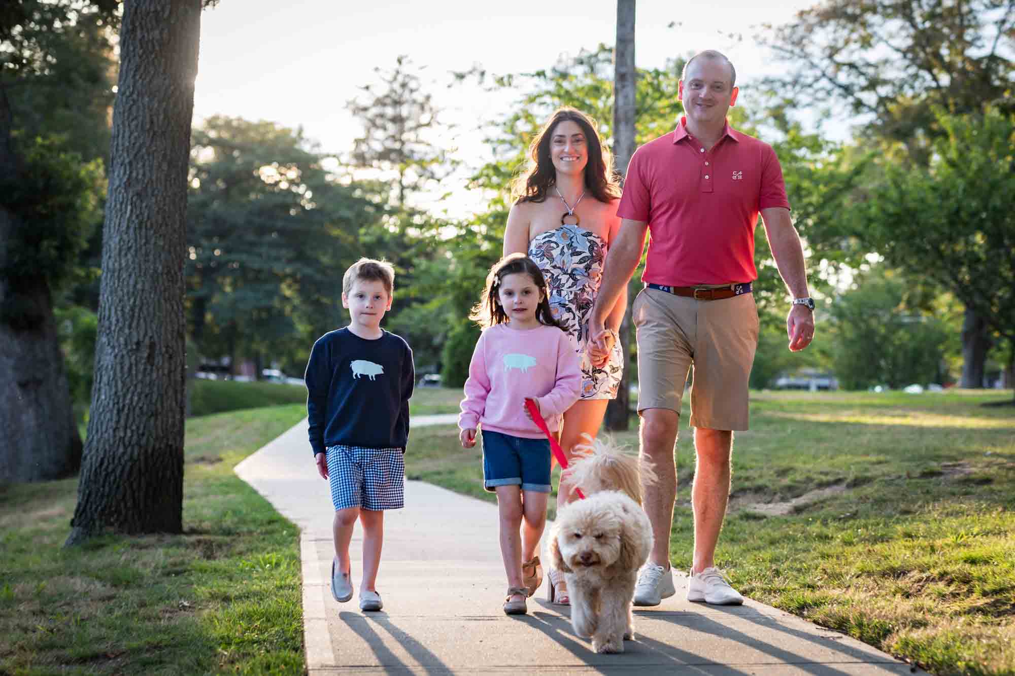 Parents, two kids and dog walking on sidewalk in Spring Lake New Jersey park