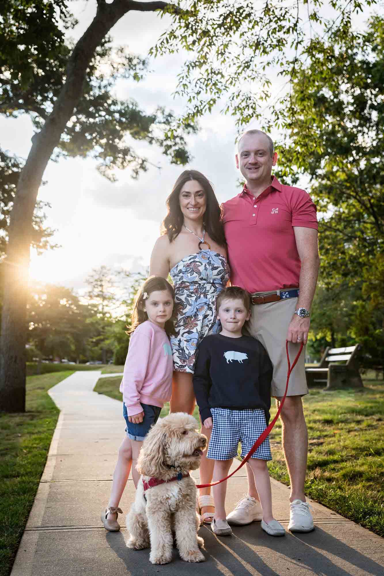 Parents, two kids and dog standing on sidewalk in Spring Lake New Jersey park