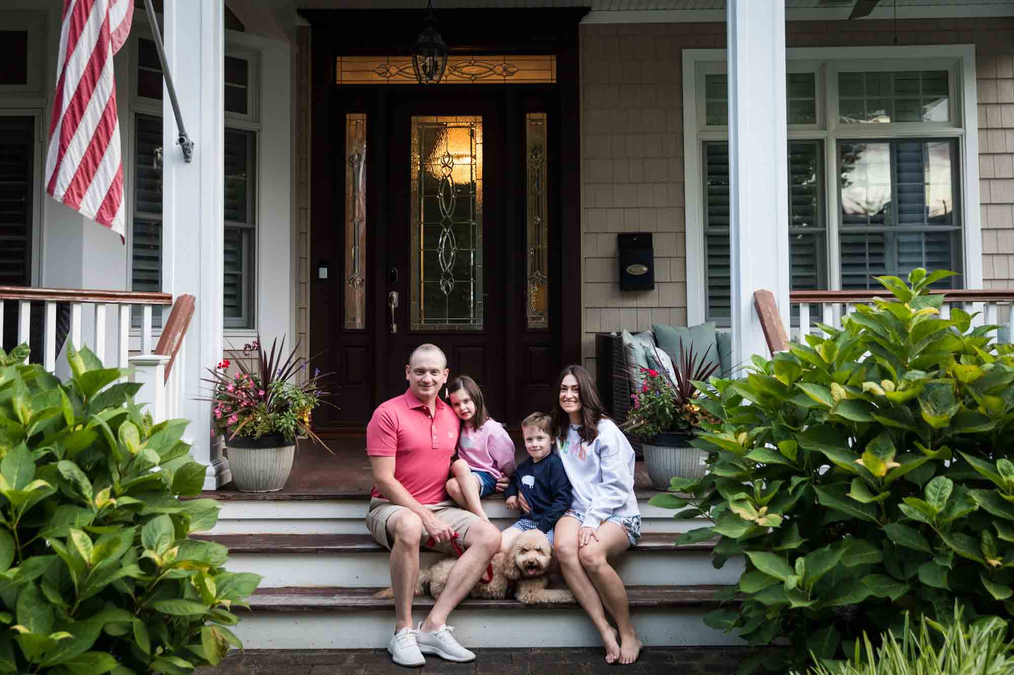 Parents and two kids sitting on steps in front of house in Spring Lake, New Jersey 