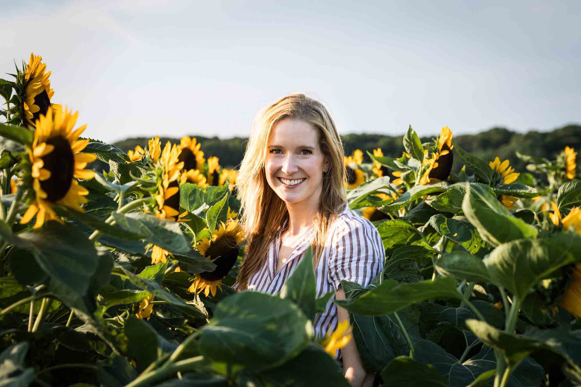 Blonde woman standing in middle of sunflower patch