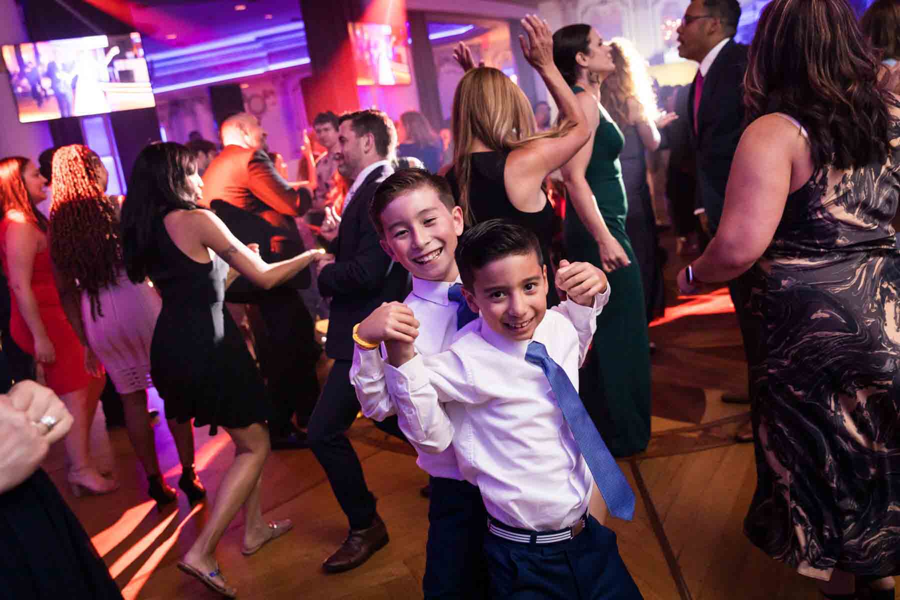 Two little boys dancing in front of guests at a Terrace on the Park wedding