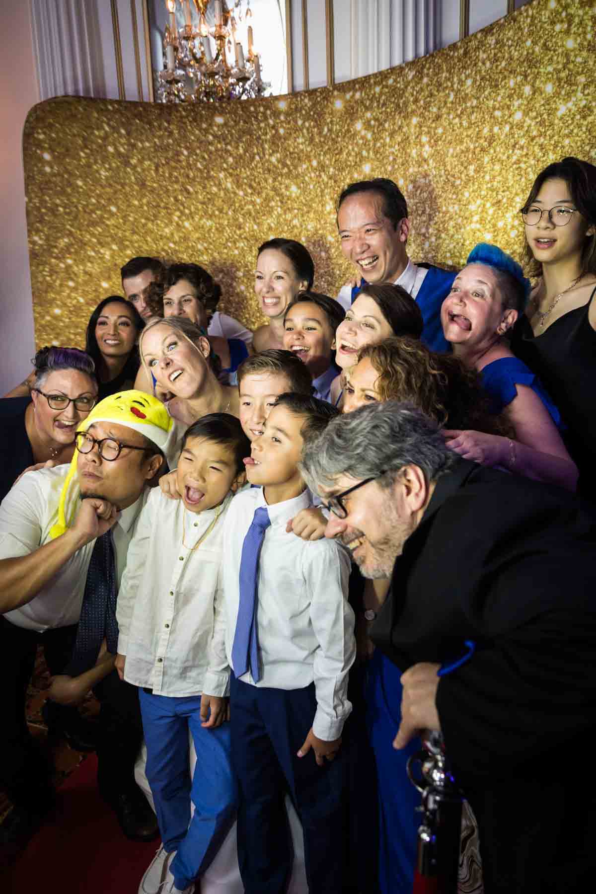 Guests piled up in front of gold background at a photo booth at a Terrace on the Park wedding