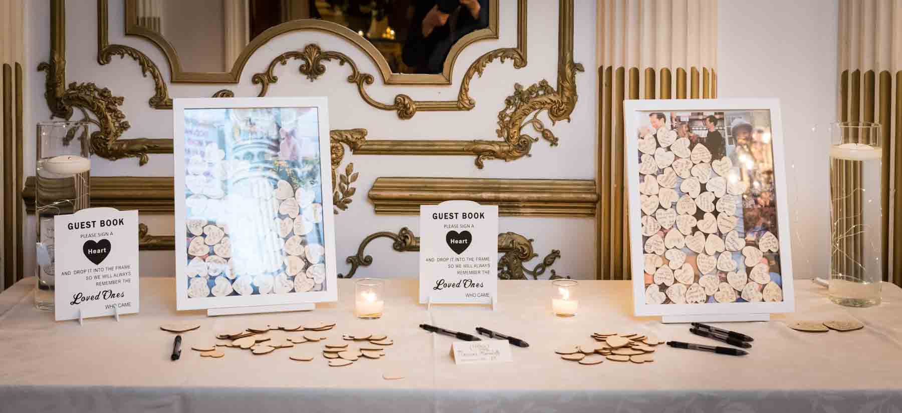 Table displaying guest book with wooden hearts and white frames