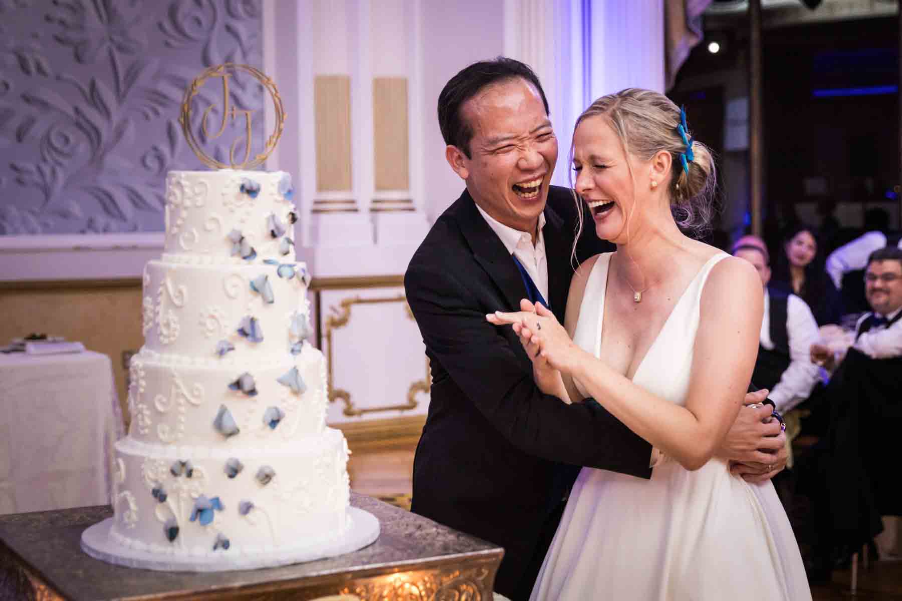 Bride and groom laughing and hugging in front of cake at a Terrace on the Park wedding