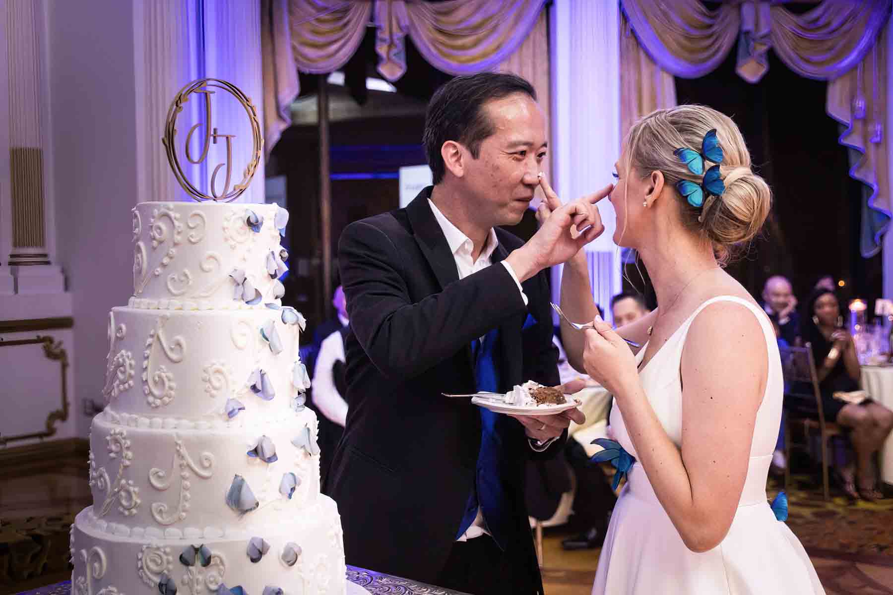Bride and groom putting icing on their noses in front of cake at a Terrace on the Park wedding