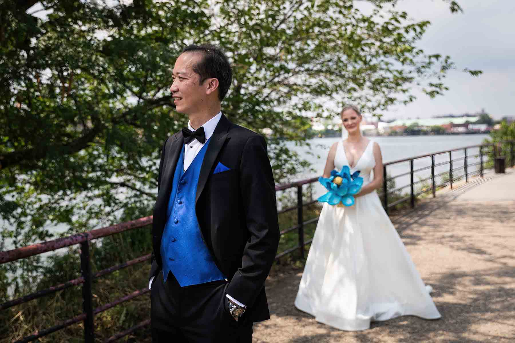 Bride looking at groom during first look along waterfront in Astoria Park