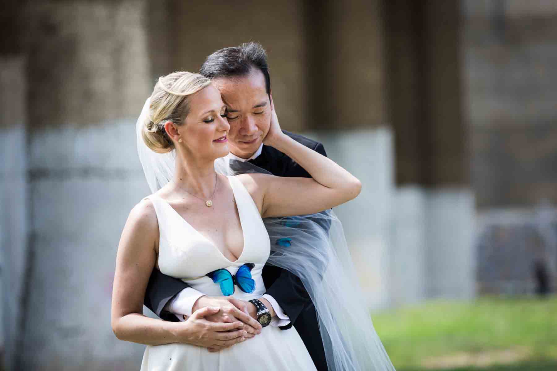Groom hugging bride from behind in Astoria Park