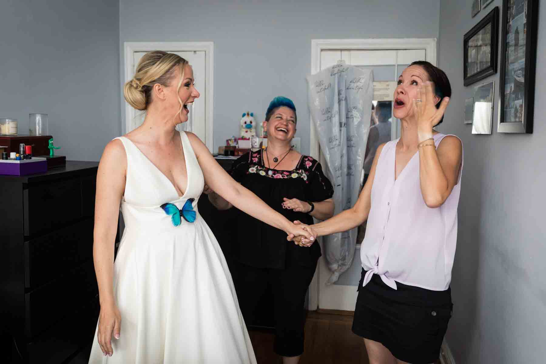 Bride and two bridesmaids in bedroom before wedding