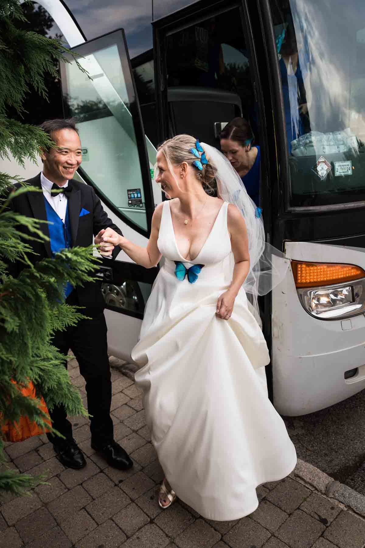 Groom holding bride's hand as she gets out of bus