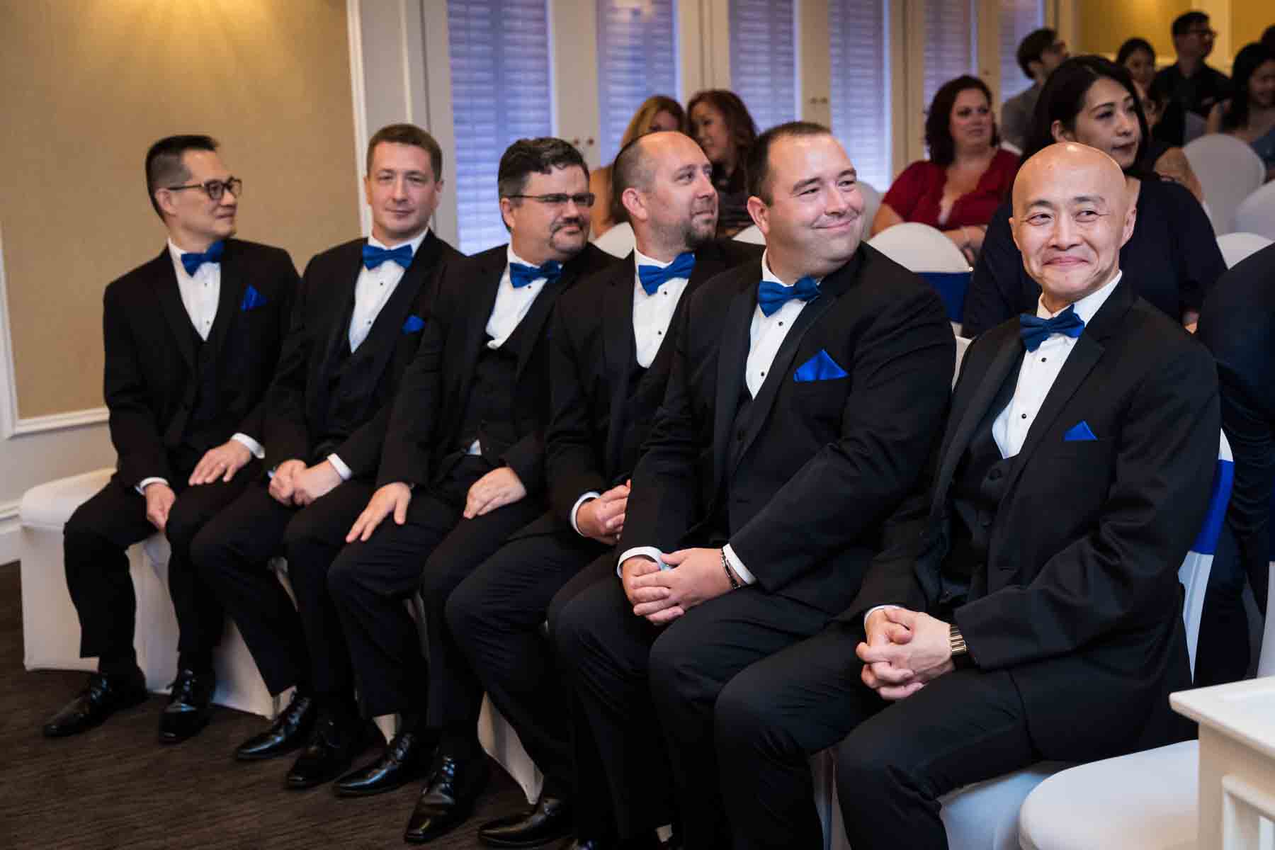 Groomsmen sitting in front row during ceremony at a Terrace on the Park wedding
