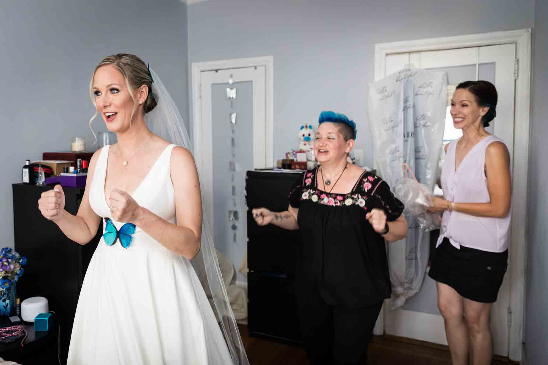 Bride and two bridesmaids with excited faces in bedroom before wedding