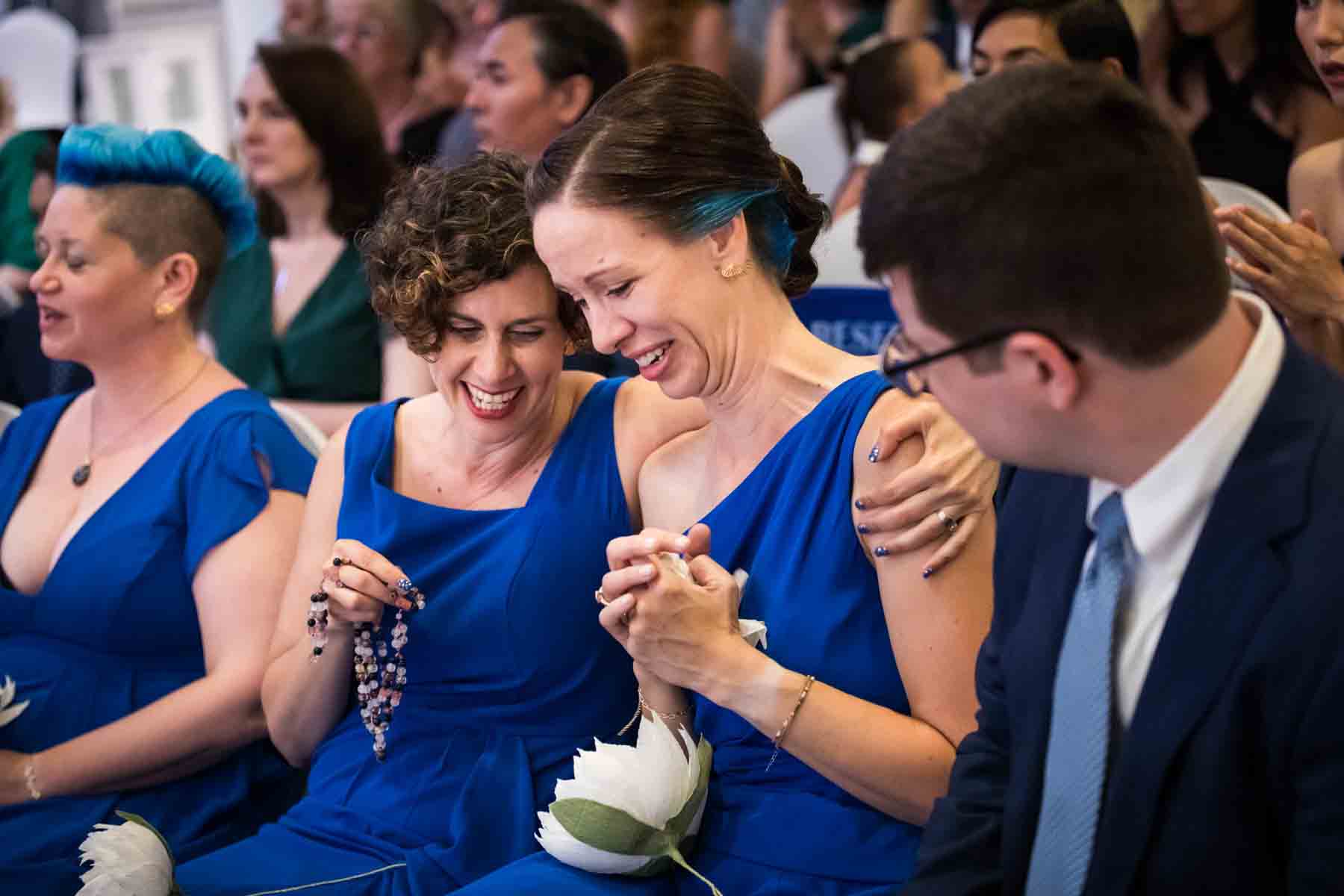 Two bridesmaids hugging while seated at a Terrace on the Park wedding