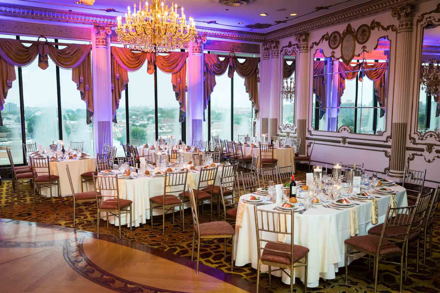 Reception room set with five tables and grand chandelier at a Terrace on the Park wedding