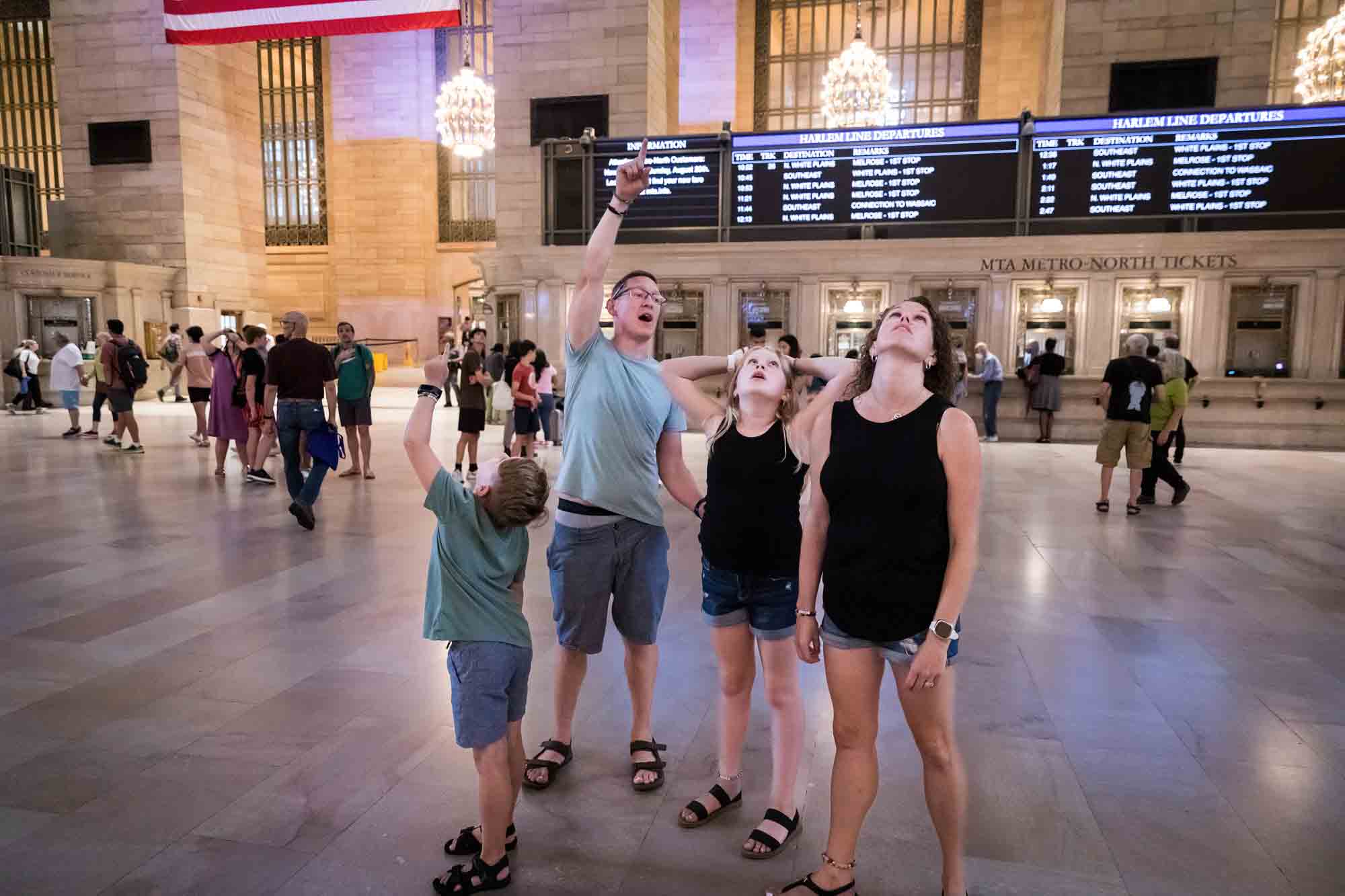 Parents pointing out ceiling to two kids in Grand Central Terminal