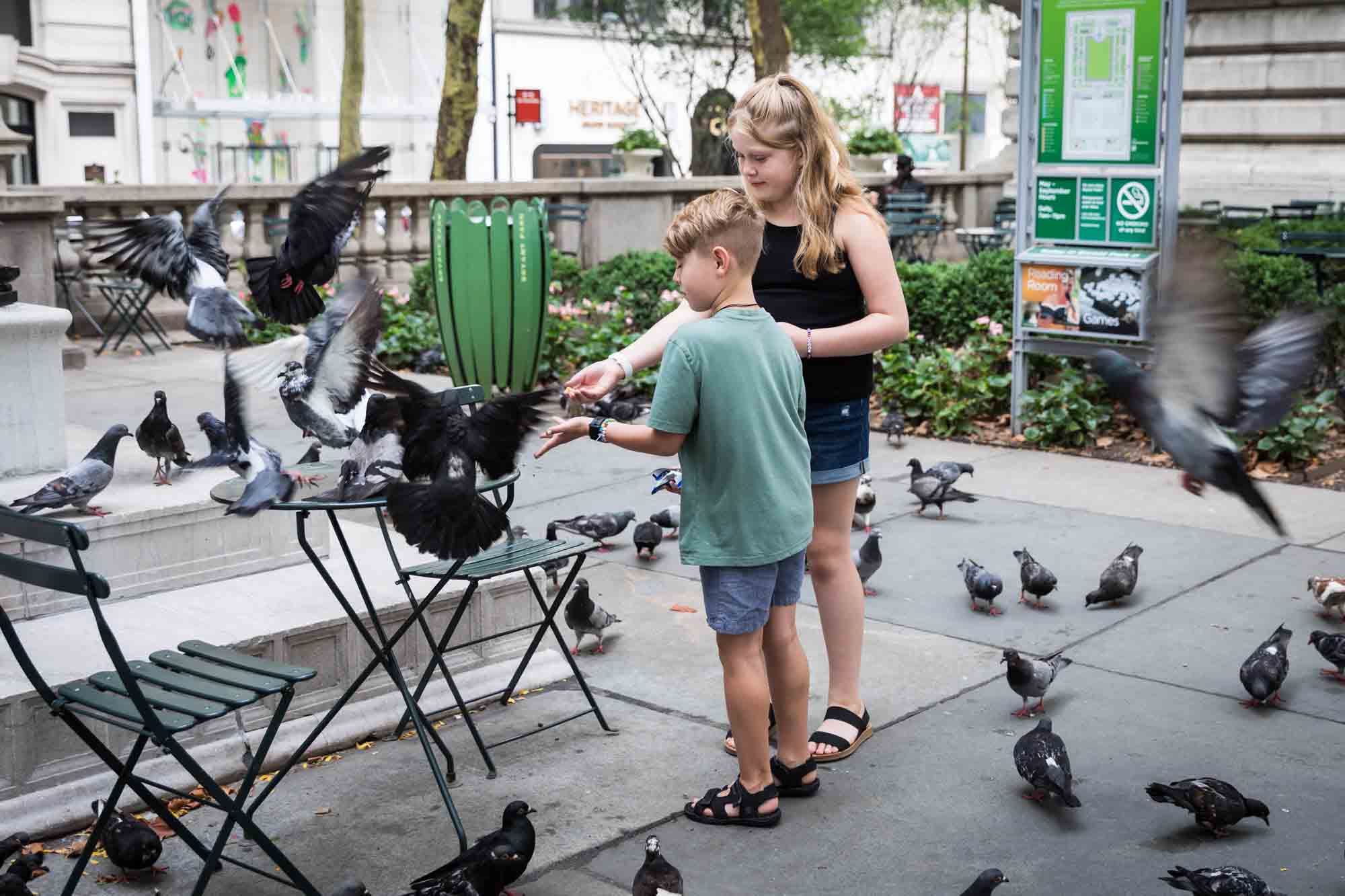 Boy and girl feeding pigeons at New York Public Library patio