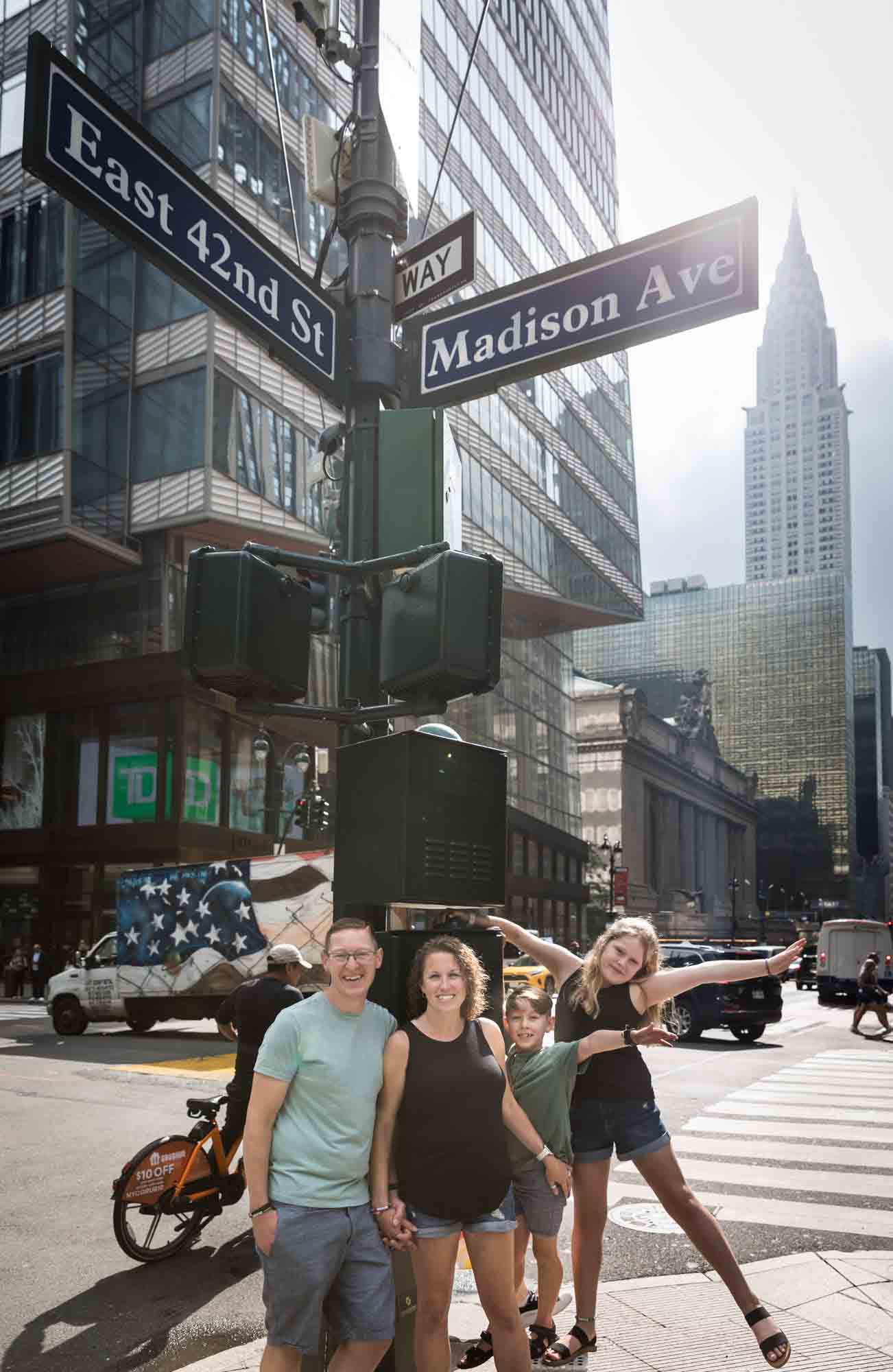 Parents and two kids standing on light pole at NYC intersection