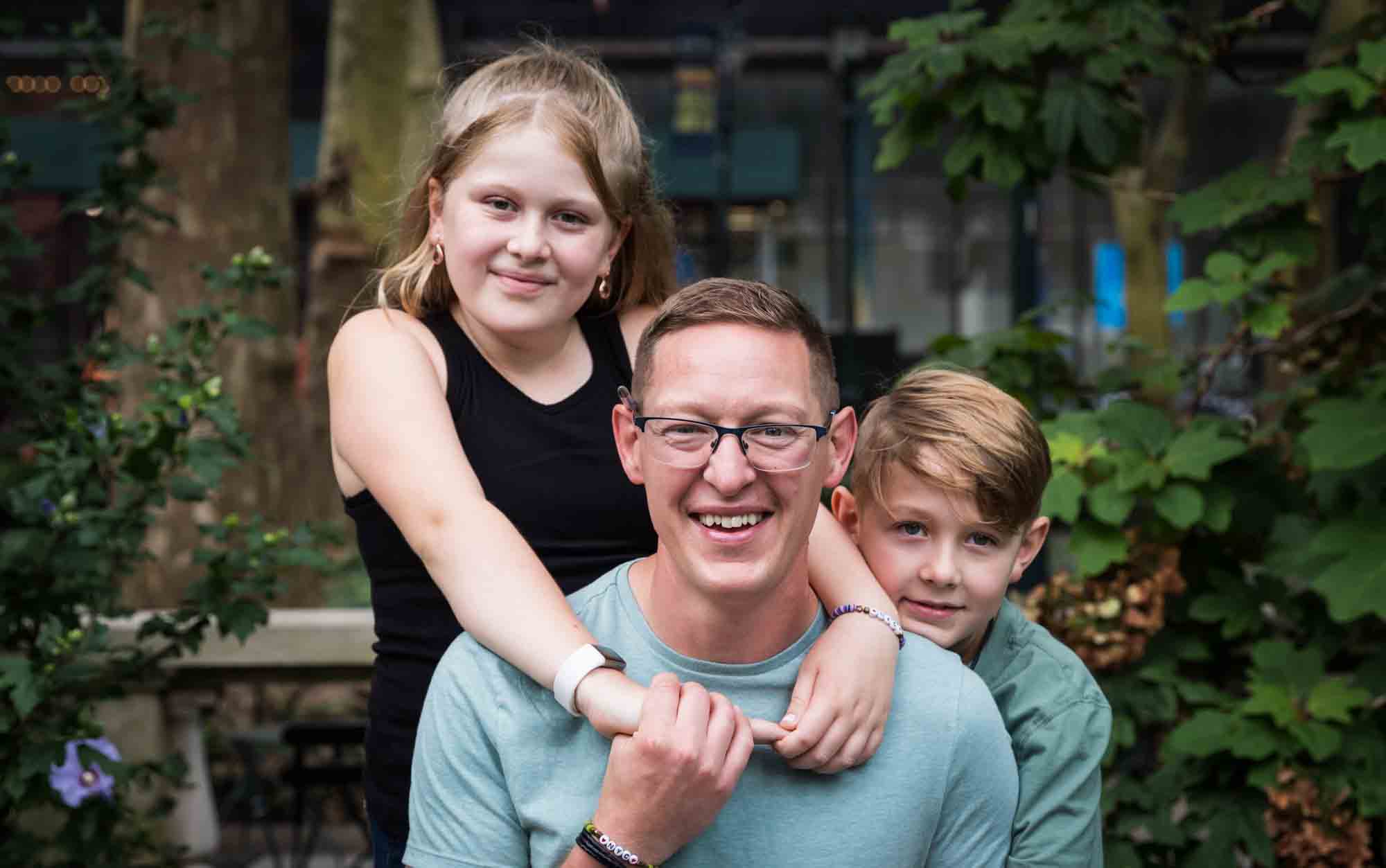 Boy and girl hugging father in Bryant Park