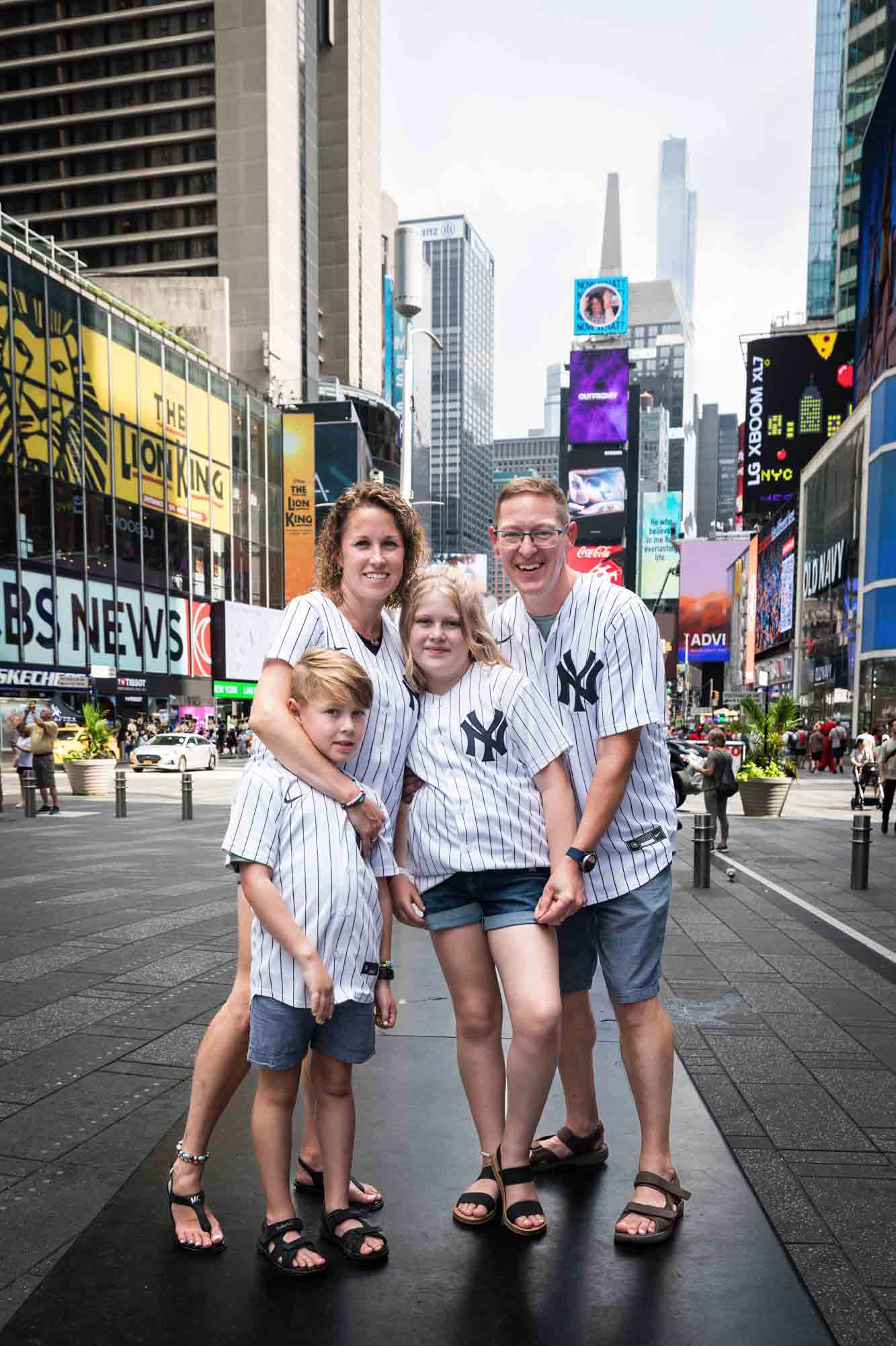 Parents and two kids wearing Yankees jerseys in Times Square for an article on best Manhattan family portrait locations