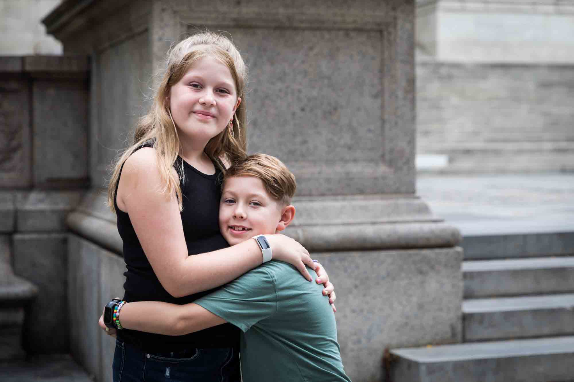Brother and sister hugging each other in front of New York Public Library