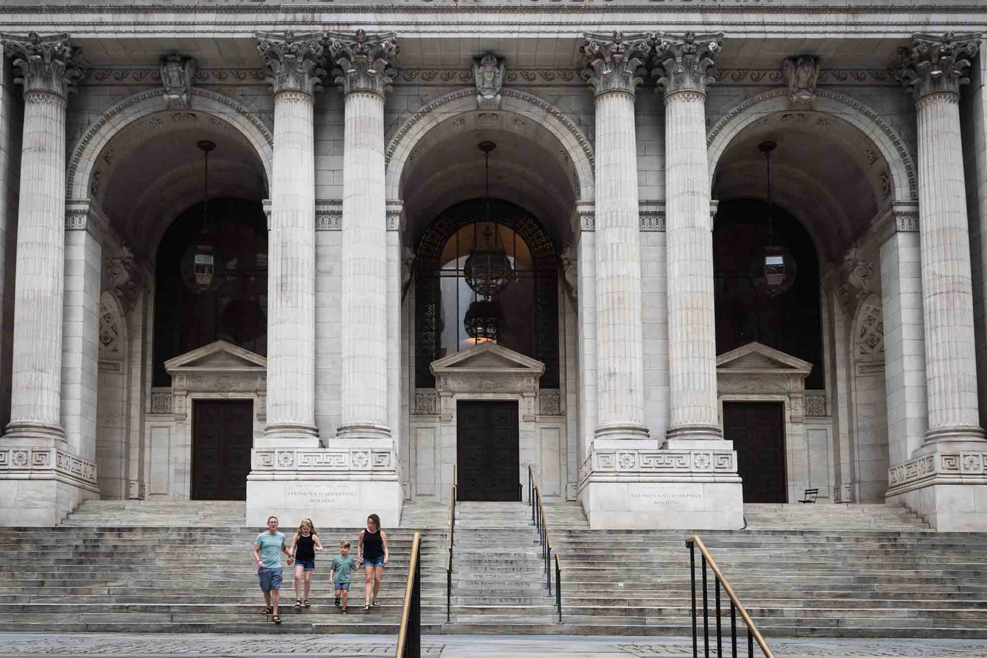 Parents and two kids walking down steps of New York Public Library for an article on best Manhattan family portrait locations