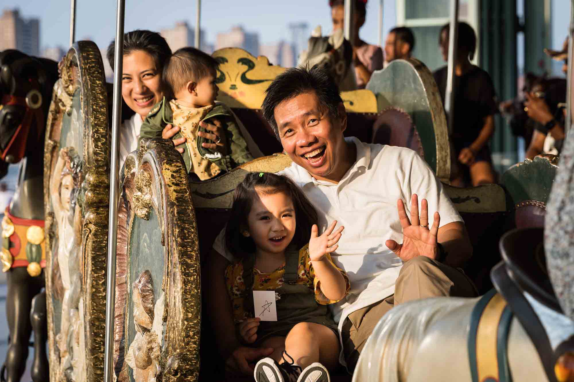 Parents with young daughters in carriage on Jane's Carousel in Brooklyn Bridge Park