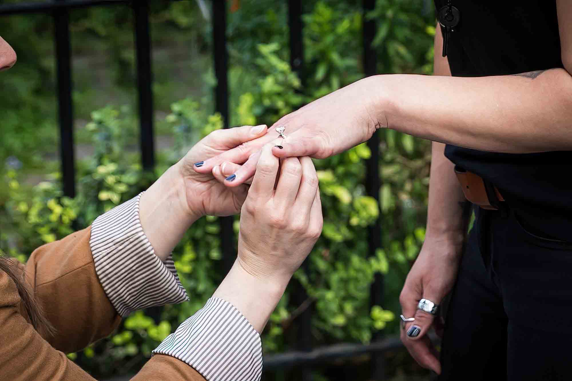 Close up of woman putting engagement ring on another woman's hand