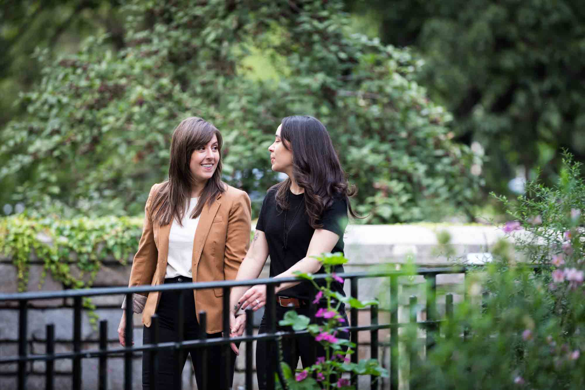 Two women walking in Riverside Park in front of gate and flowers for an article on how to produce a movie-themed surprise proposal