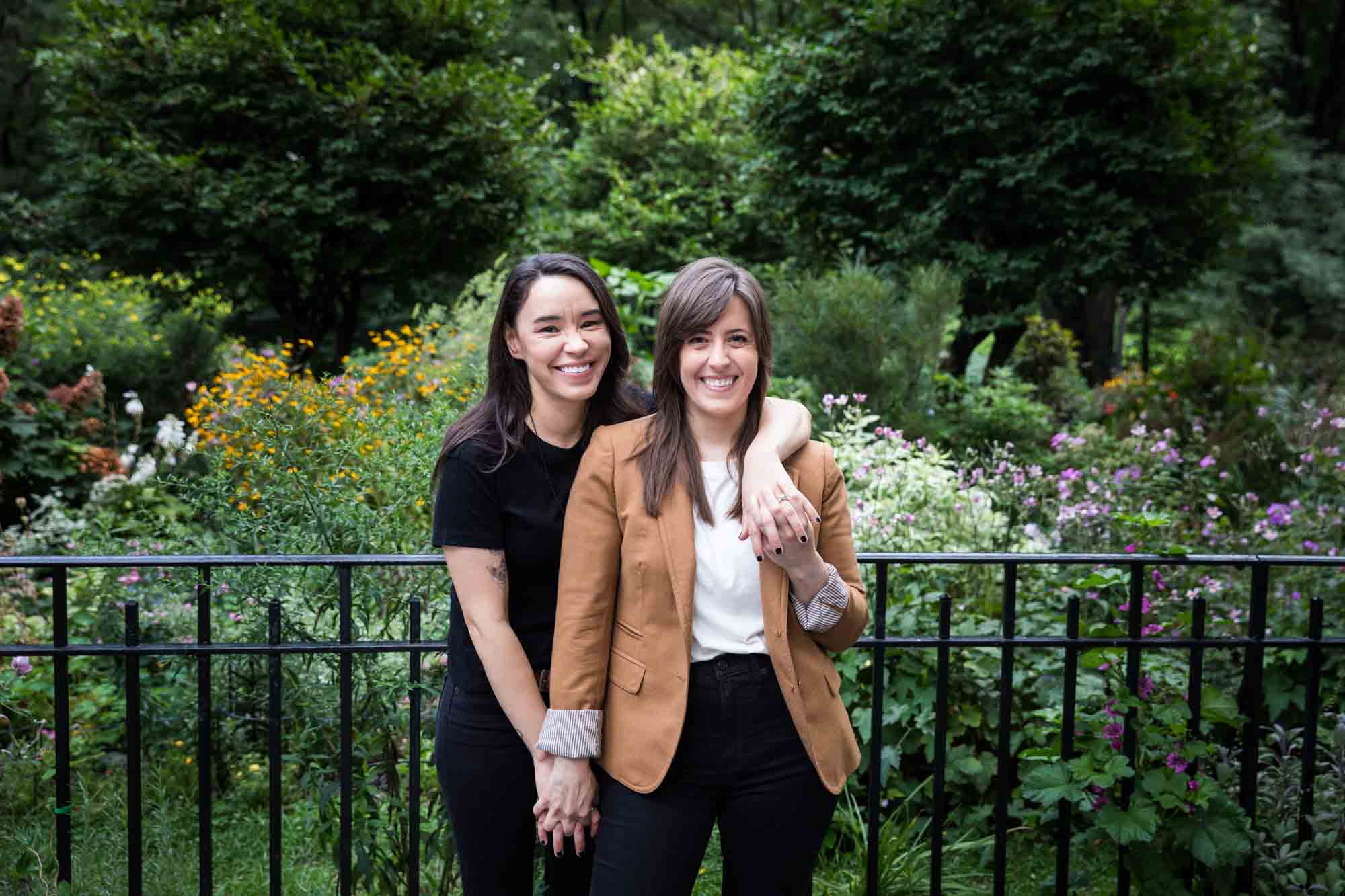 Two women standing in Riverside Park in front of gate and flowers for an article on how to produce a movie-themed surprise proposal