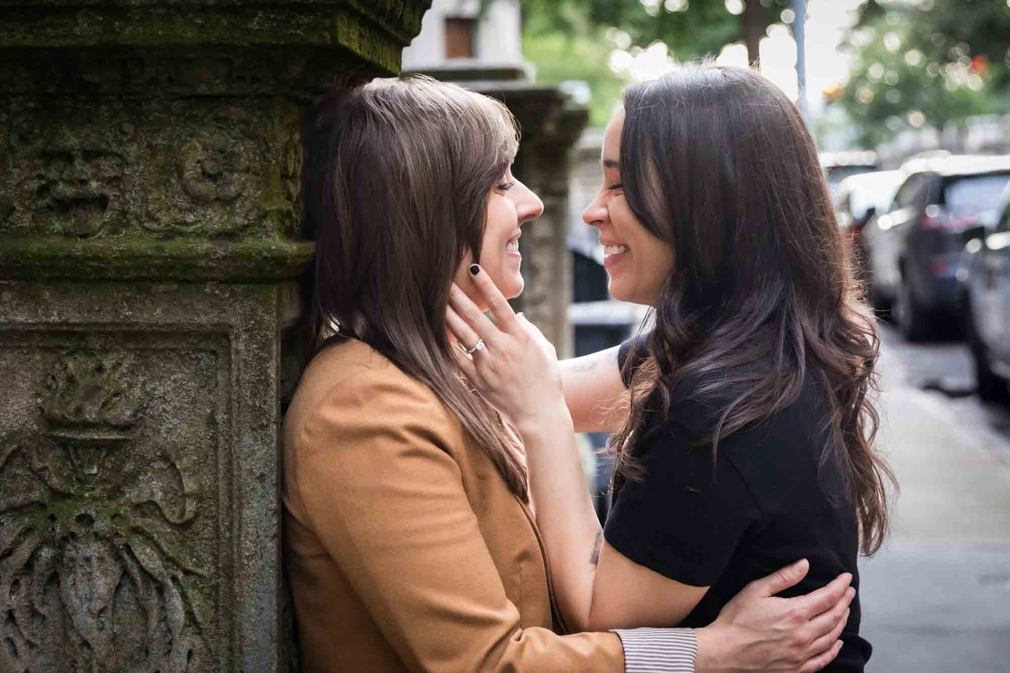 Two women about to kiss against a stone staircase pillar for an article on how to produce a movie-themed surprise proposal