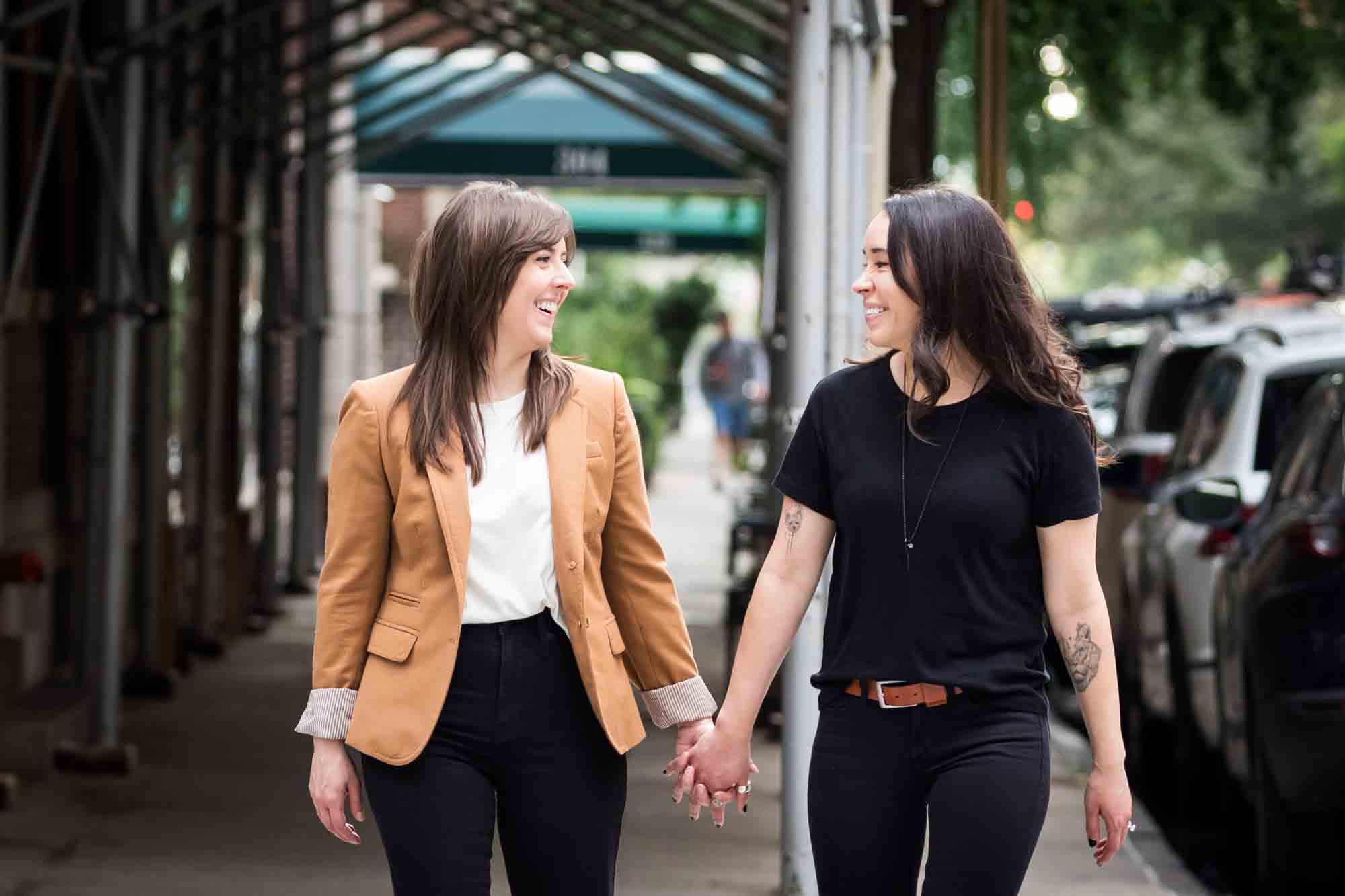 Two women holding hands and walking in a crosswalk in NYC for an article on how to produce a movie-themed surprise proposal