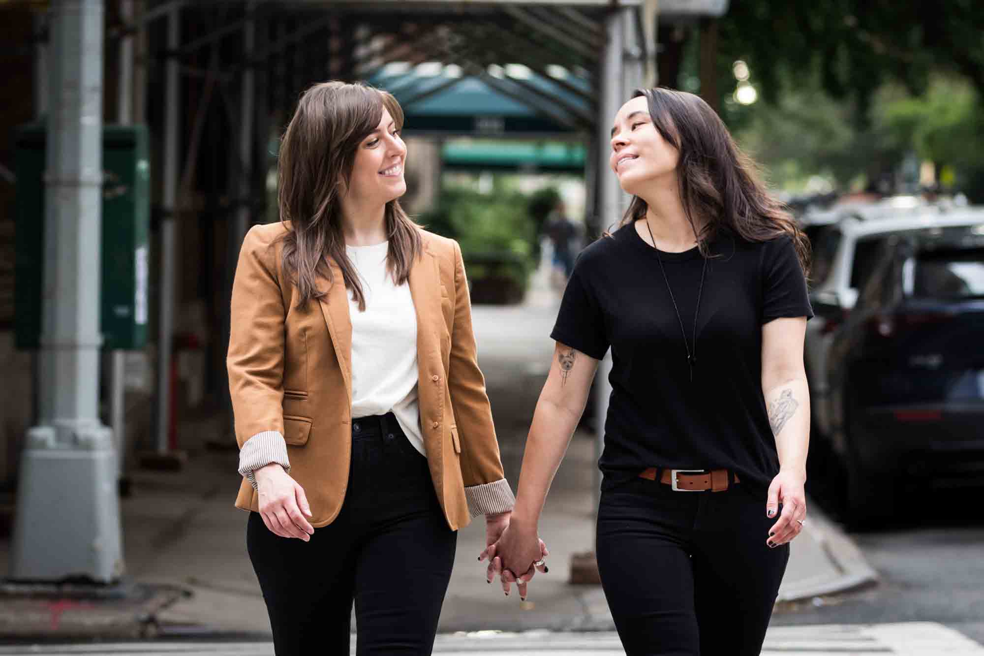 Two women holding hands and walking in a crosswalk in NYC for an article on how to produce a movie-themed surprise proposal