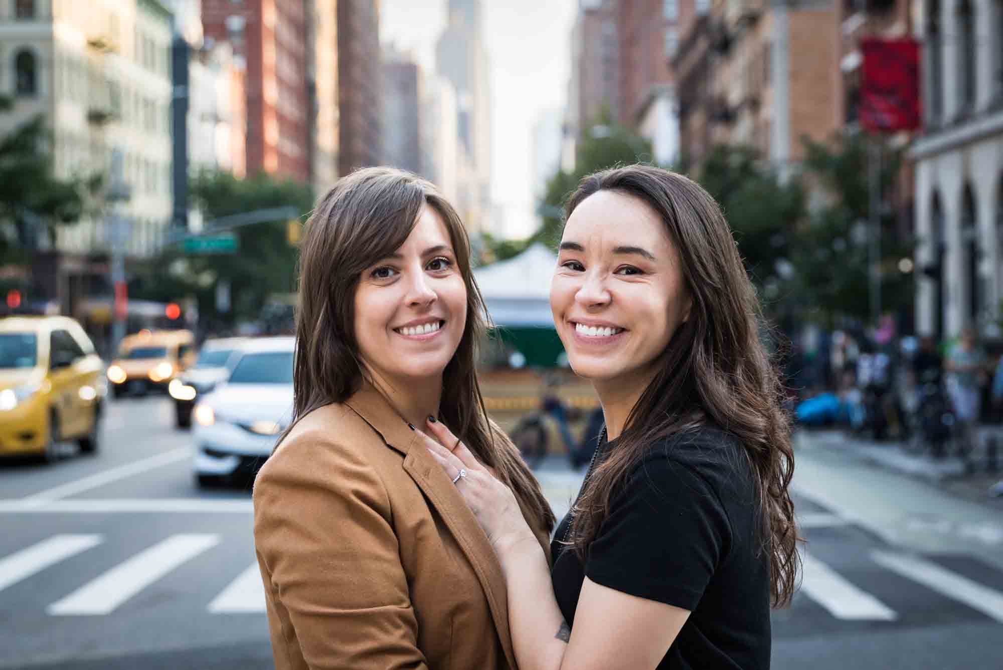 Two women cuddled together on the streets of NYC with traffic in the background