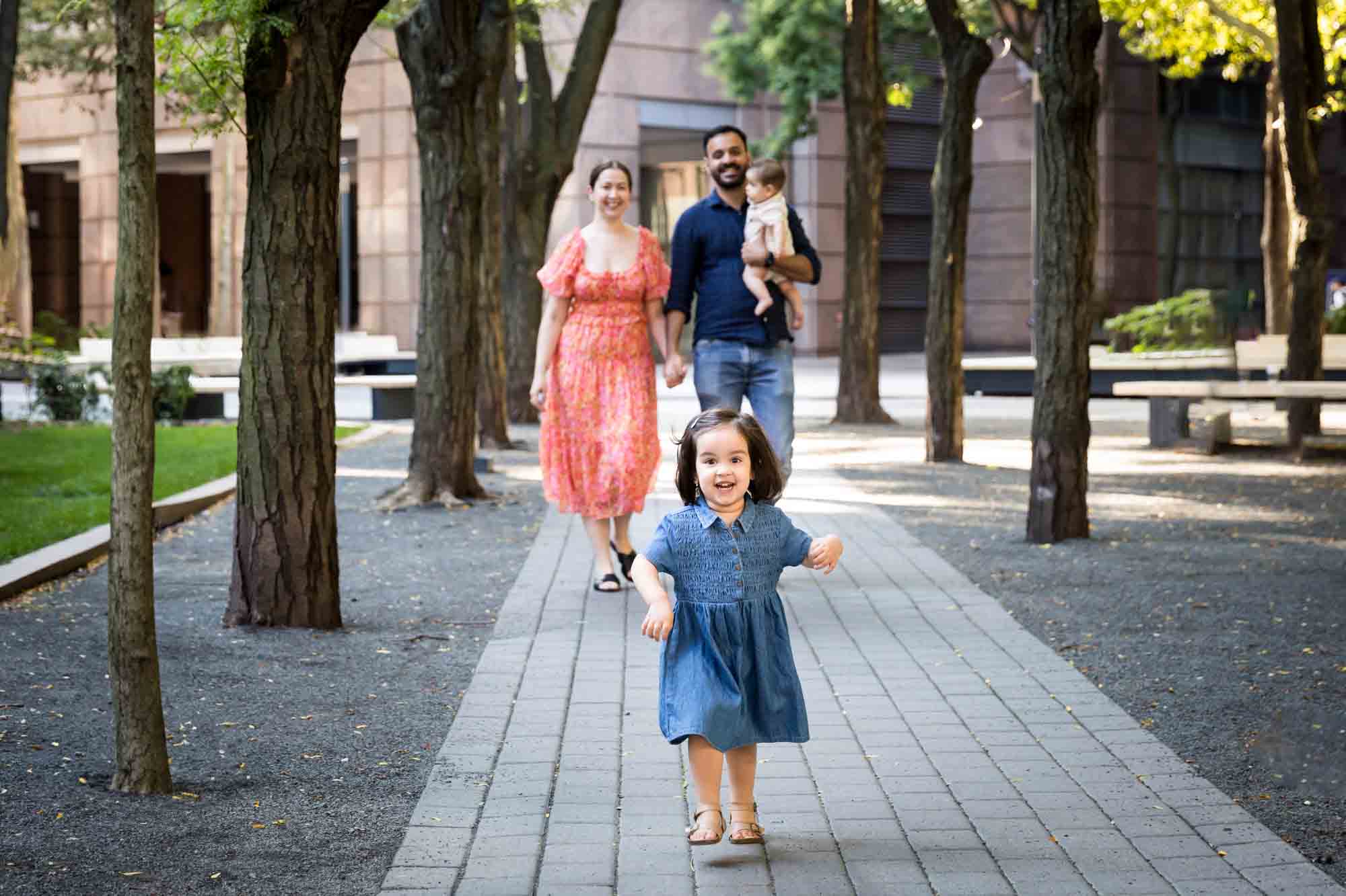 Parents with baby and little girl walking down stone pathway during a Brooklyn Commons family portrait session