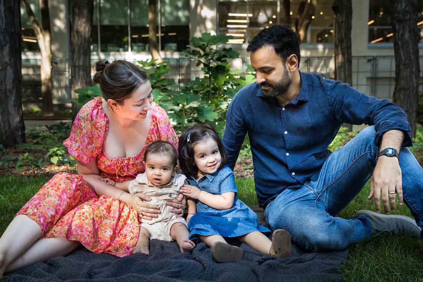 Parents sitting on gray blanket with baby girl and boy during a Brooklyn Commons family portrait session