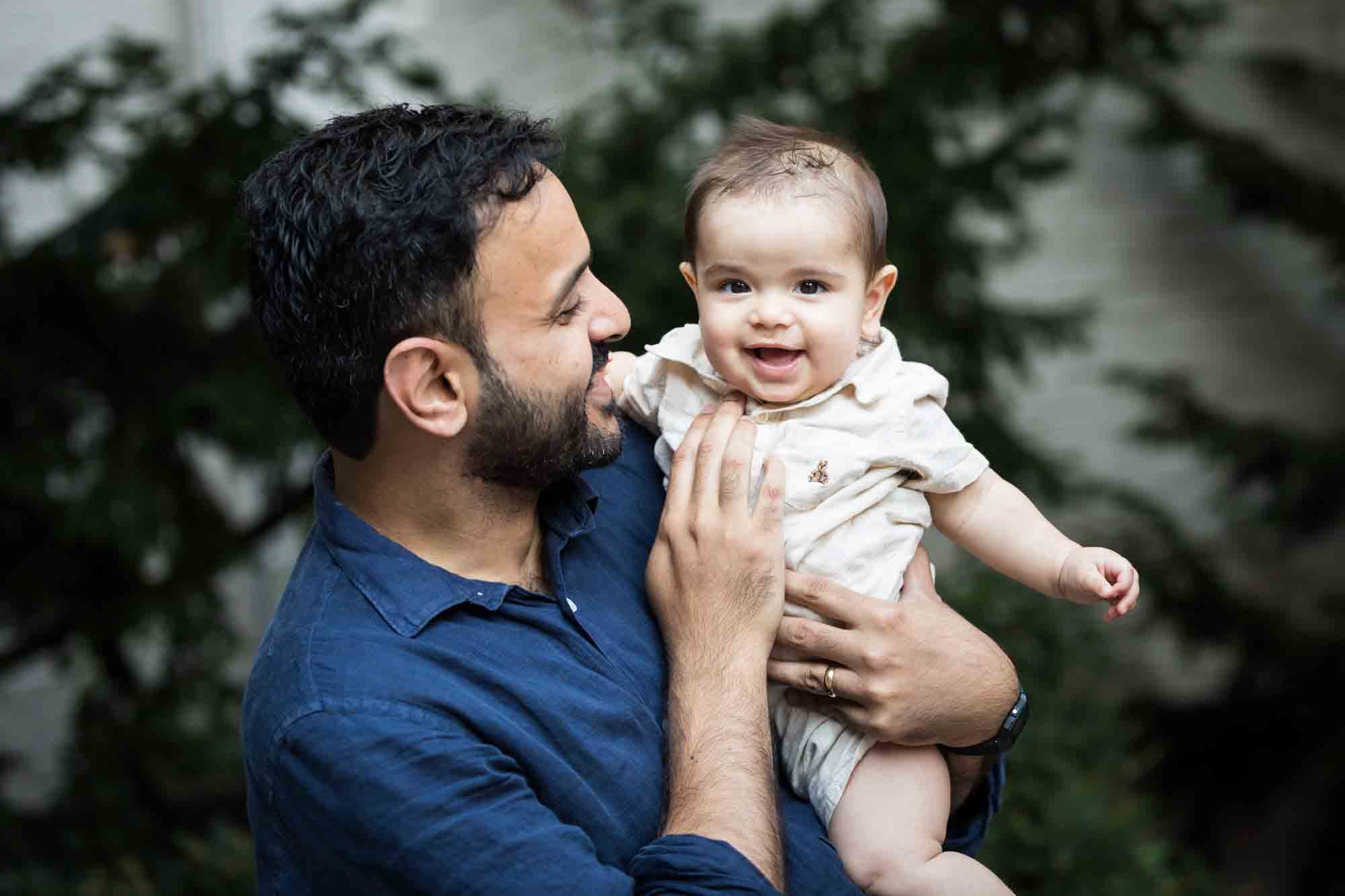 Father wearing blue shirt holding baby boy during a Brooklyn Commons family portrait session