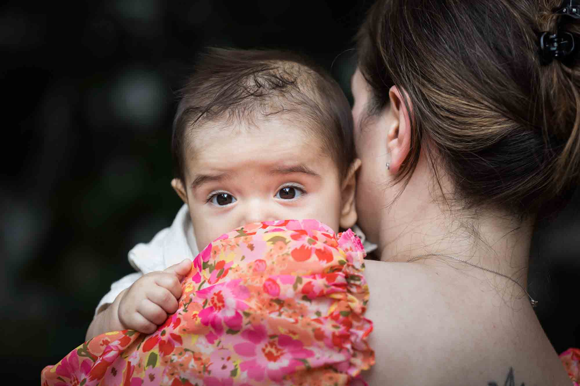 Mother in red floral dress holding baby boy during a Brooklyn Commons family portrait session