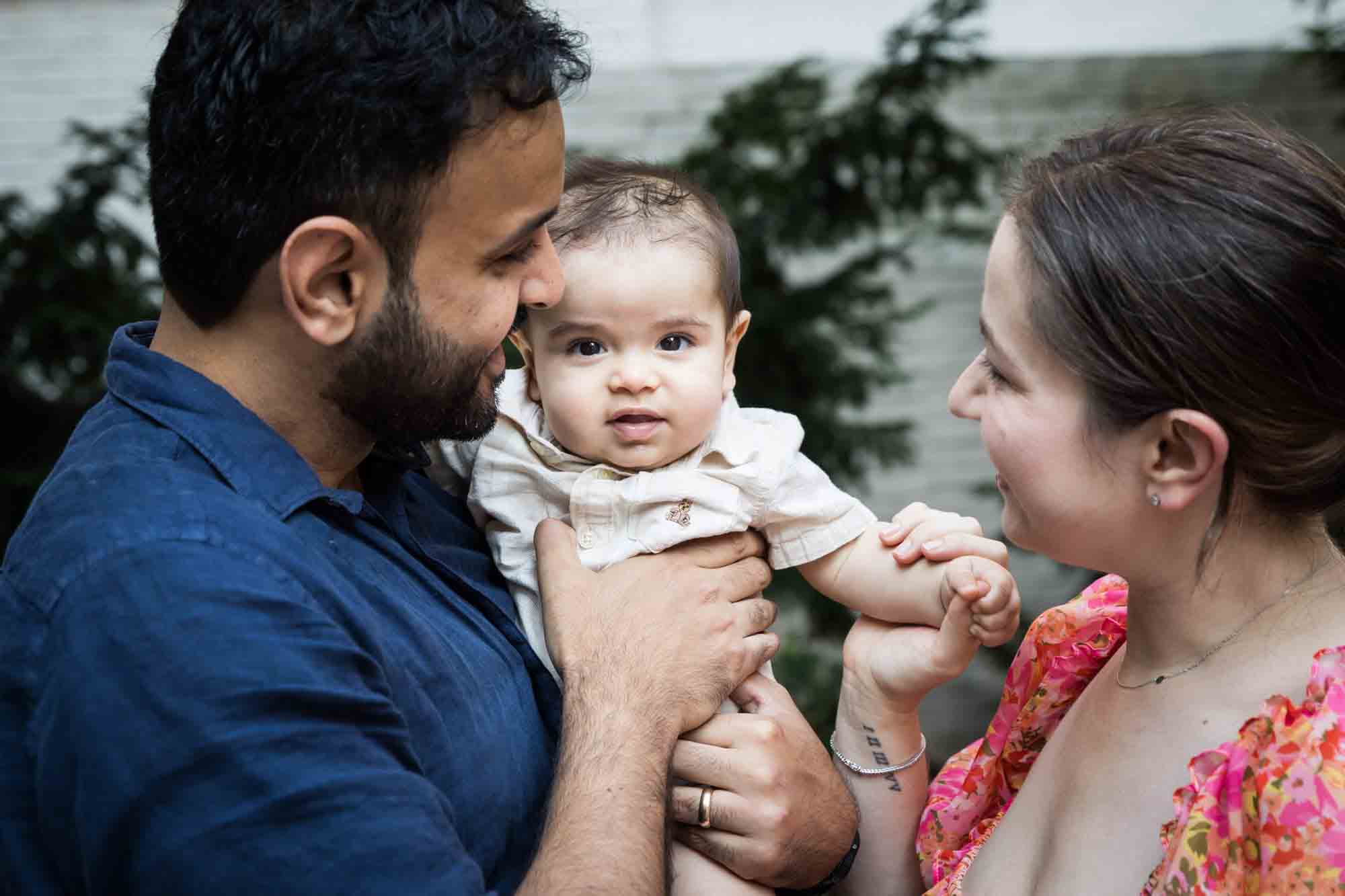 Parents holding little boy in front of vine-covered wall during a Brooklyn Commons family portrait session