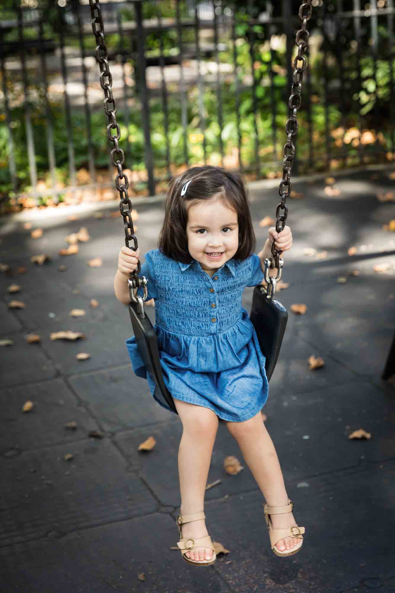 Little girl in blue dress in swing at McLaughlin Park in Brooklyn