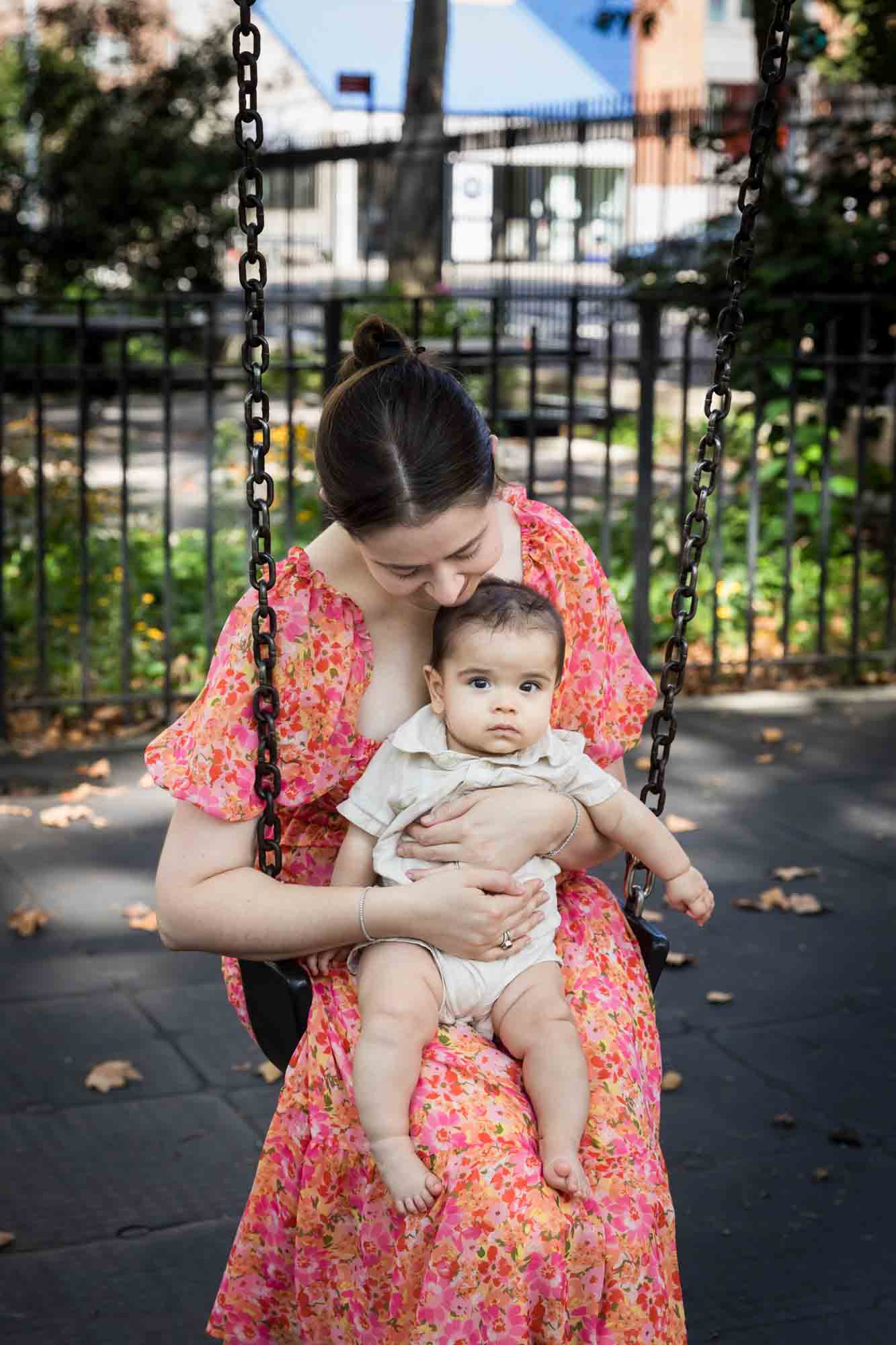 Mother in floral dress holding little boy in swing at McLaughlin Park