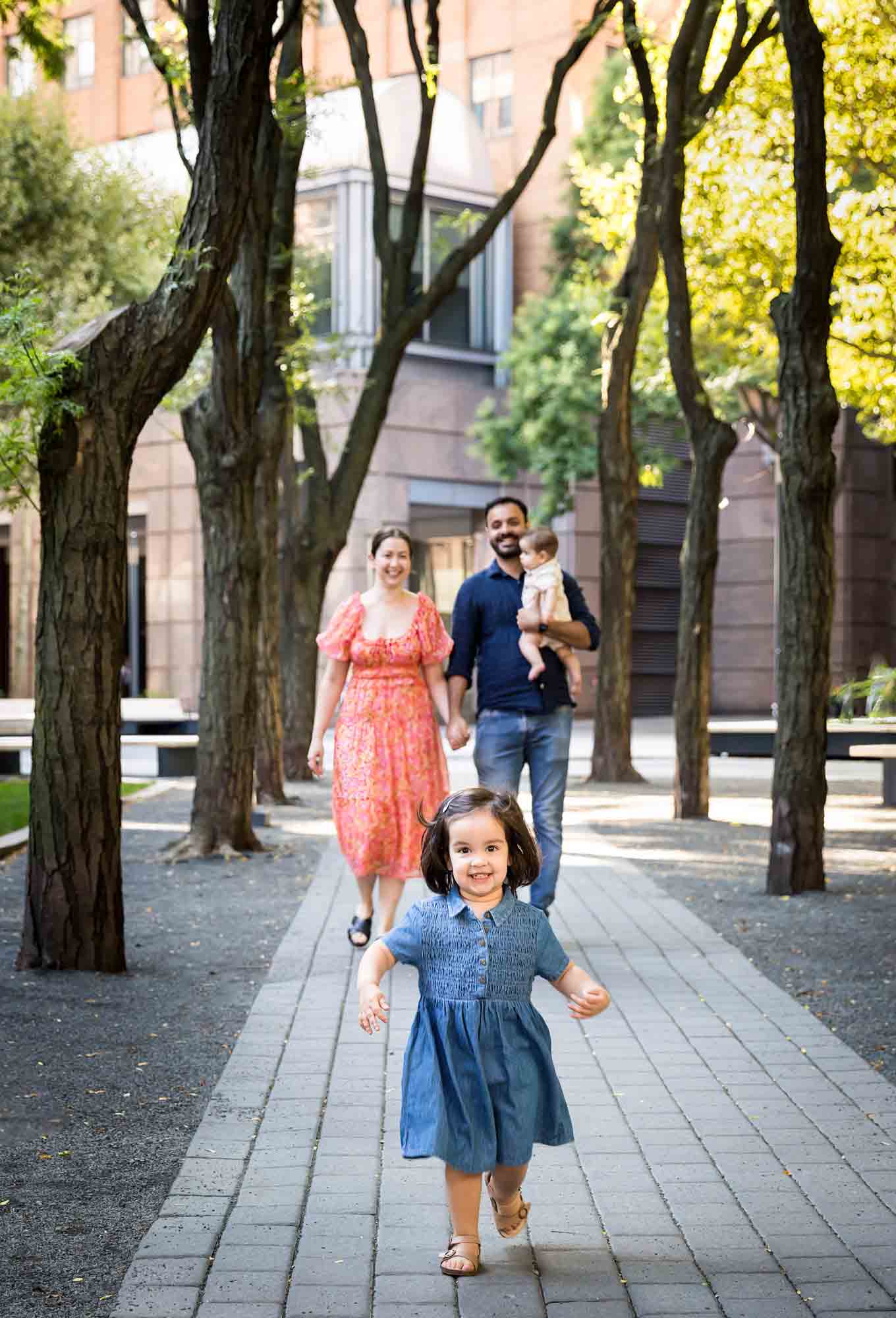 Parents with baby and little girl walking down stone pathway during a Brooklyn Commons family portrait session