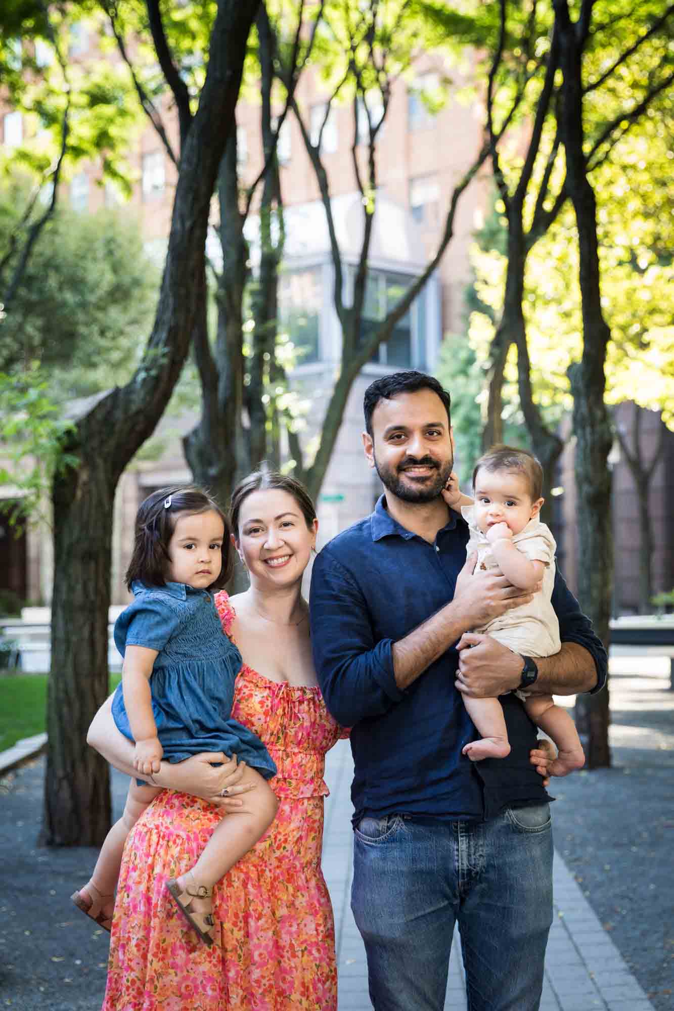Parents with baby and little girl standing on pathway during a Brooklyn Commons family portrait session